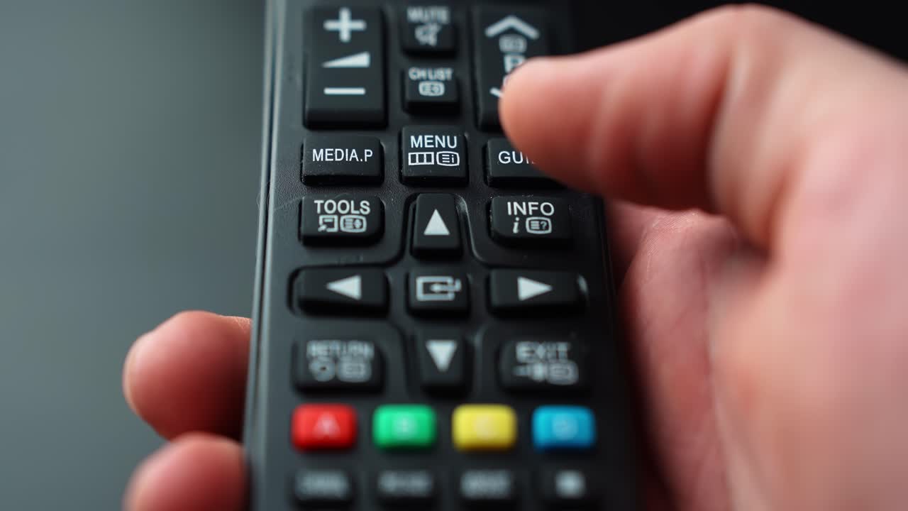 Close-up of a hand pressing the UP arrow on a TV remote, navigating upward through an on-screen menu with shallow depth of field for home entertainment tech b-roll