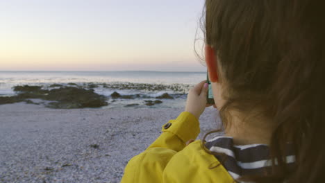 turista usando un teléfono en una playa para fotografiar