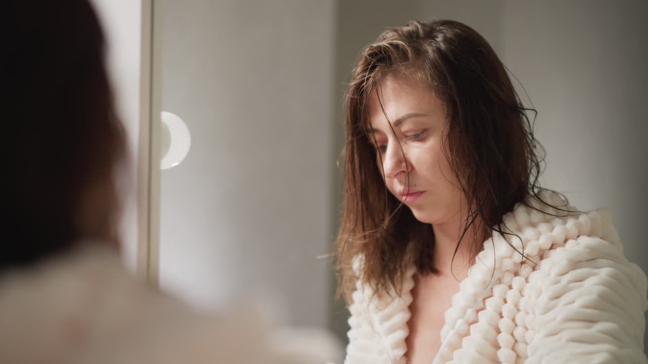 Lady wipes remained water drops on mirror with cleansing towel. Woman cleans up numerous wet drops after taking bath in trendy shower slow motion