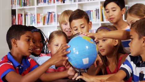 niños de la escuela estudiando el globo en la biblioteca