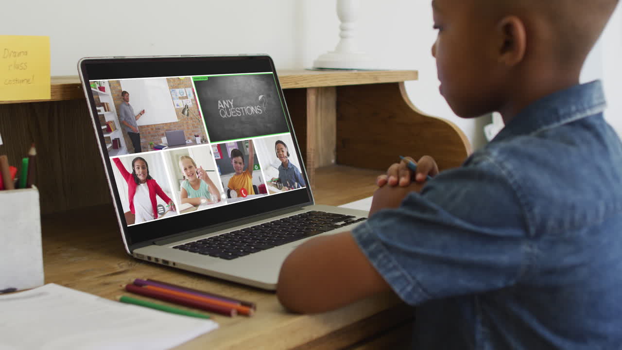 niño afroamericano teniendo una videoconferencia con el maestro y los compañeros de clase en la computadora portátil en casa