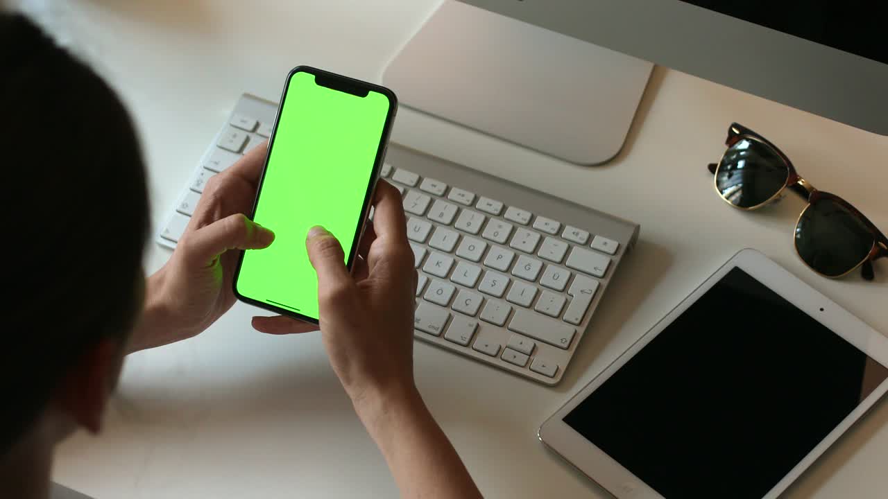 persona que sostiene un teléfono móvil con pantalla verde en la mano