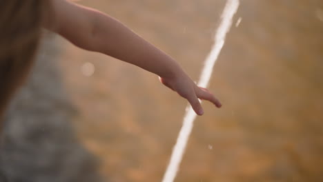 little girl touches fountain water on city street closeup