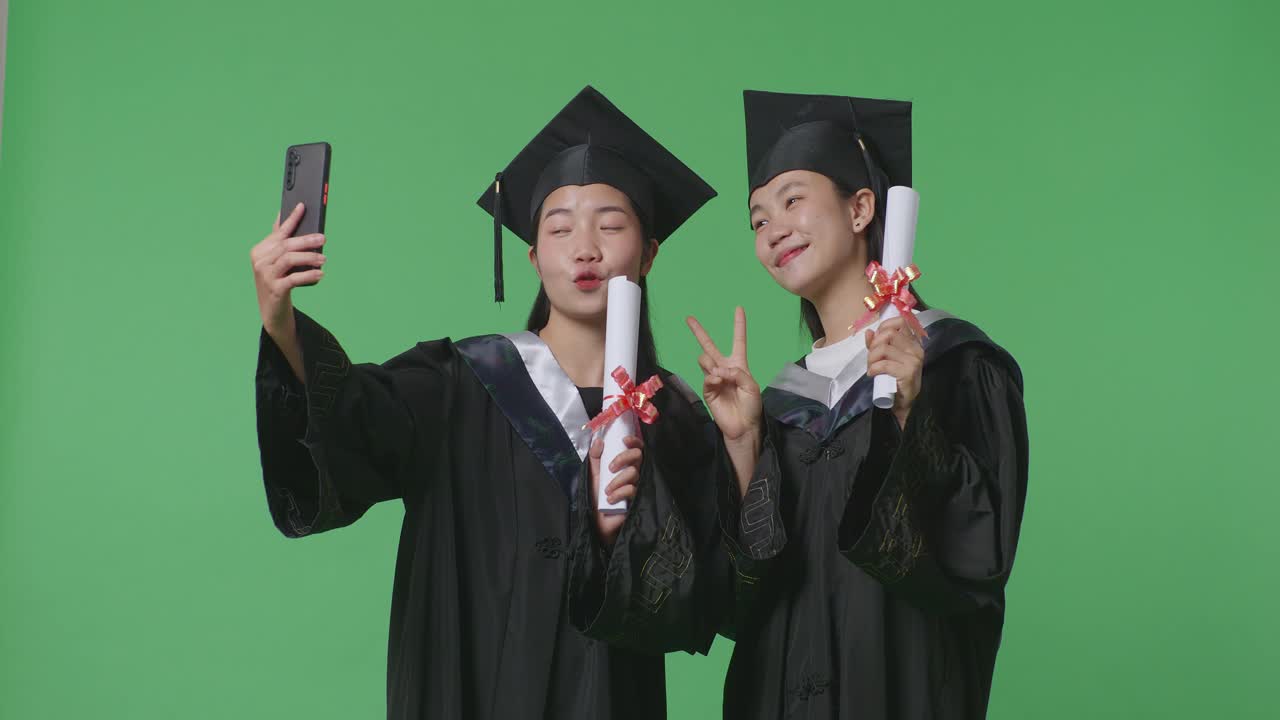 두 명의 졸업생 여성이 셀피를 찍고 있습니다.