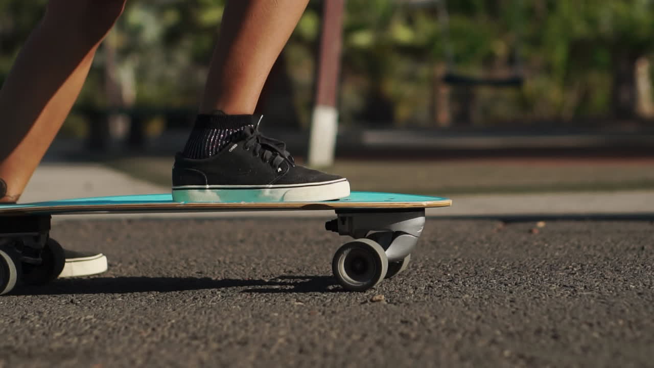 Slow motion captures the essence of summer as a young woman rides a longboard near palm trees, donning shorts and sneakers