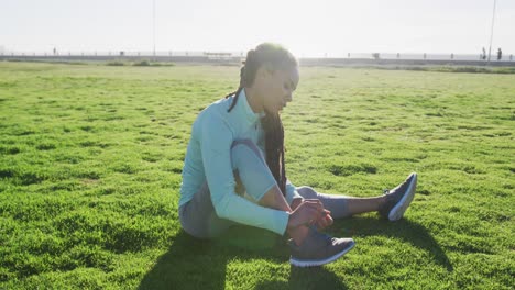 mujer afroamericana en ropa deportiva atando sus cordones en el parque