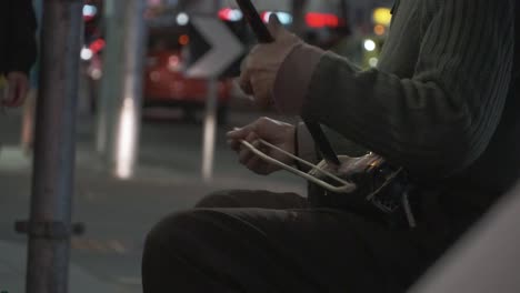 close up of a cute chinese old man's hand playing the stork on the china town of melbourne australia city with the background of moving traffic and lights