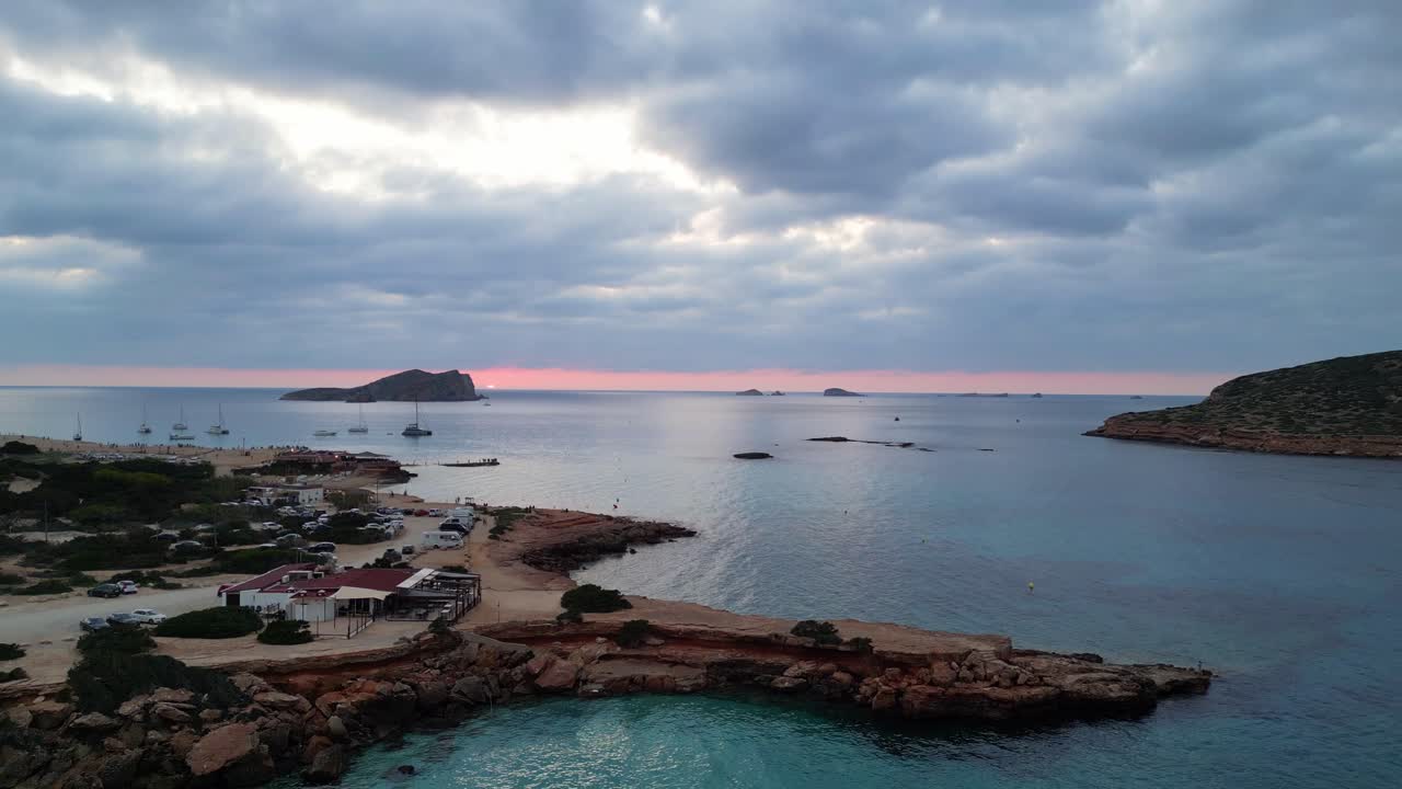 Ylhäältä otettu upea ilmakuva auringonlaskusta pilvisellä taivaalla Ibizan Cala Comten rannalla Espanjassa.
