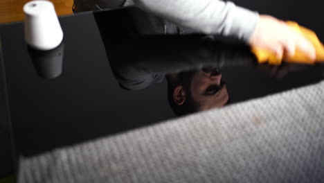 Reflection-Of-A-Man-Cleaning-Table-With-Glass-Surface