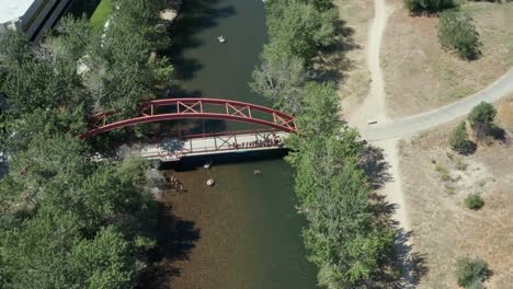 circling drone footage of people jumping off a red bridge into boise river