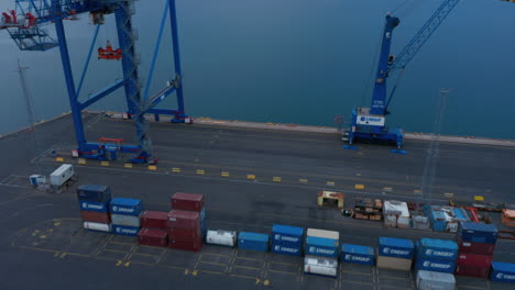 Fly-over-rows-on-transport-containers-in-terminal-in-harbour.-Tilt-up-reveal-of-water-surface-and-mountains-in-distance.-Reykjavik,-Iceland