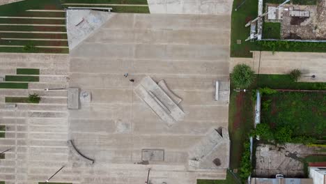 Drone-gentle-rise-up-and-look-down-over-kids-skating-at-skate-park