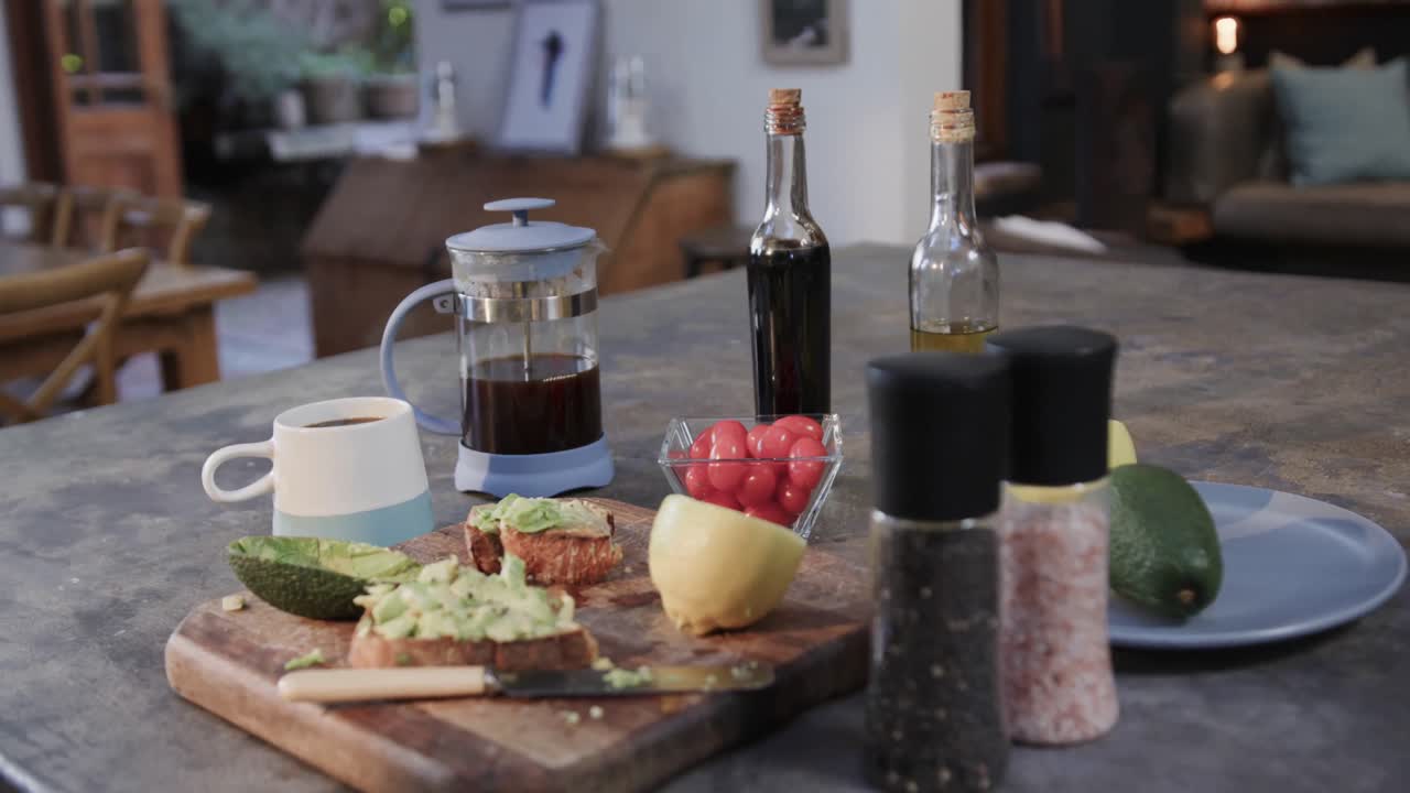 Close up of avocado sandwiches, vegetables, spices and coffee in kitchen, slow motion