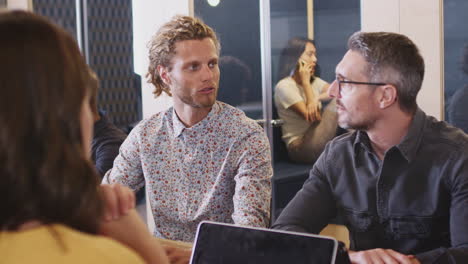 Creative-business-colleagues-talking-at-table-in-their-office-canteen,-close-up,-over-shoulder-view