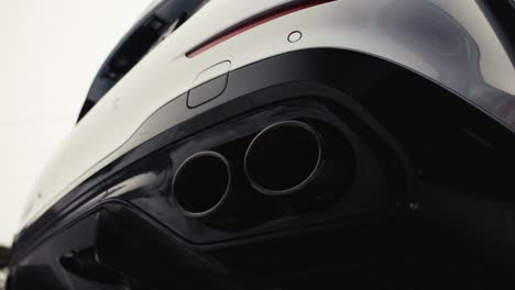 Low-angle-view-of-car-black-and-white-rear-bumper-and-round-exhaust-pipe