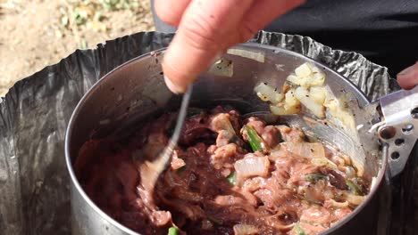 stirring up beans in a pot outside