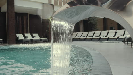 Waterfall-jacuzzi-in-hotel-spa.-Water-stop-flowing-hydromassage-fountain-in-pool