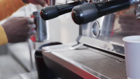 African-american-male-barista-preparing-coffee-with-coffee-machine-in-bakery-in-slow-motion