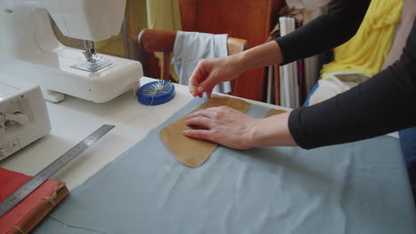 female dressmaker pinning sewing pattern to fabric