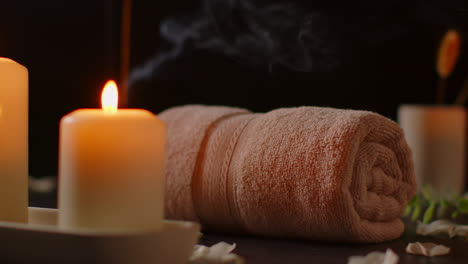 still life of lit candles with scattered petals incense stick and soft towels against dark background as part of relaxing spa day decor 3