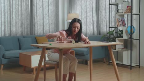 drunk, depressed asian woman with smartphone on table pouring vodka in a shot glass before drinking at the home