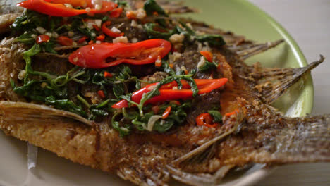 fried tilapia fish with basil chili garlic sauce on top - homemade food style