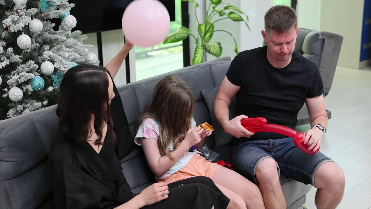 Family celebrating with balloons near a Christmas tree