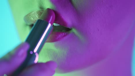 primer plano estático de los labios de una hermosa mujer llena mientras se aplica lápiz labial rojo y se prepara para la noche, la noche del club o la cita con contraste verde púrpura en su cara