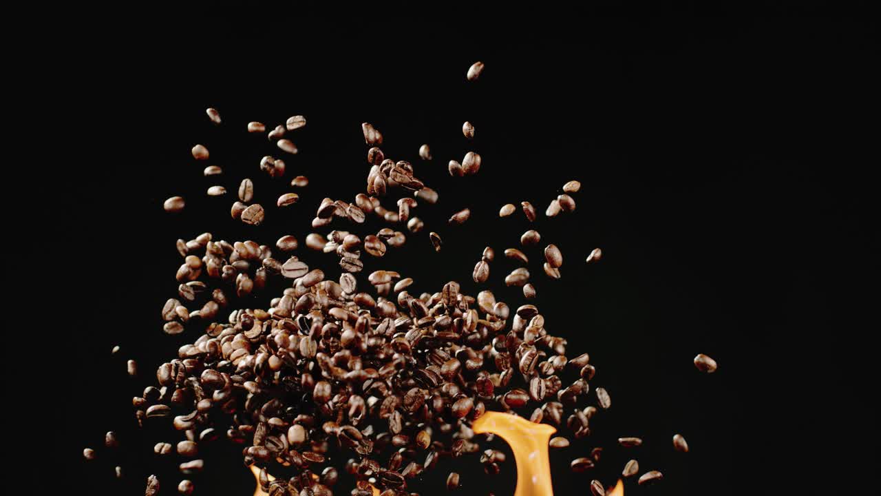 커피 콩은 검은 바탕에 불꽃 위에 공중에 날아갑니다.