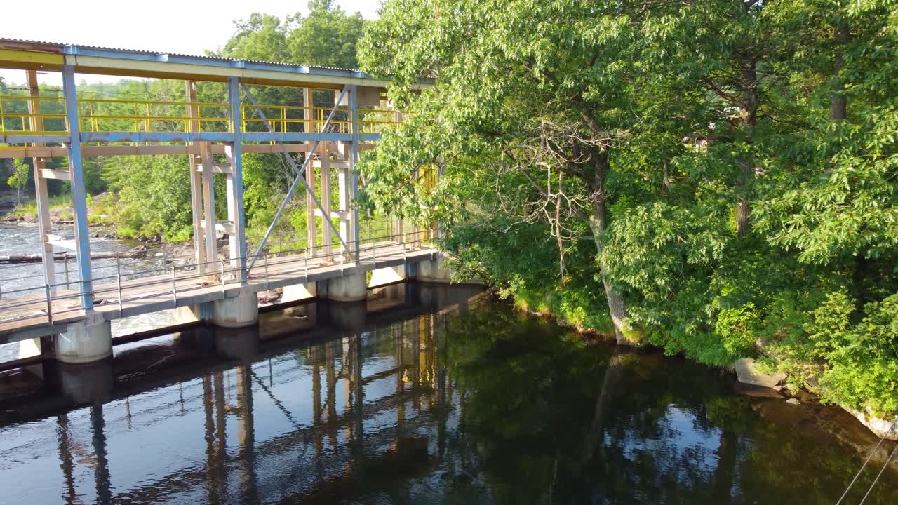vista aérea a través de un puente sobre un río que fluye a través de un bosque verde en las montañas canadienses, wasdell falls, ontario