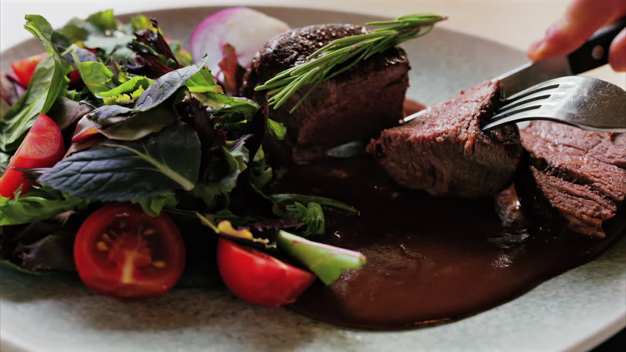 Close up of a filet mignon with a red wine sauce and a fresh salad garnish