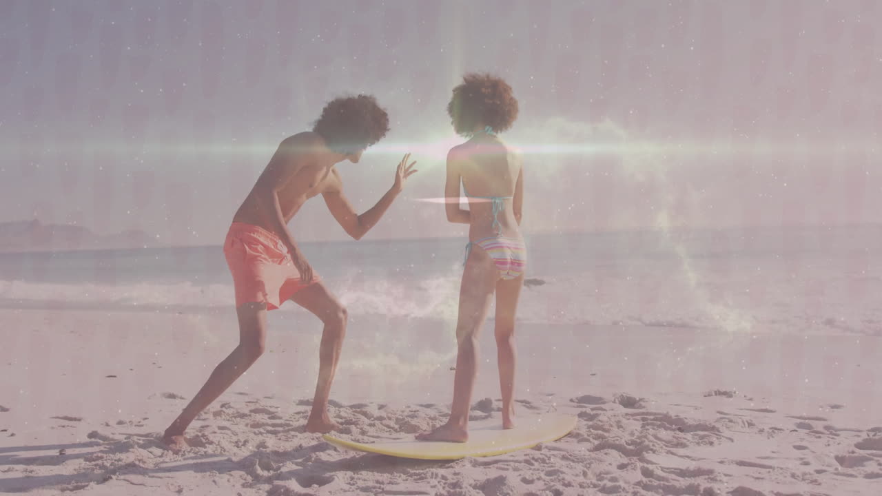 Practicing surfing techniques, two people on sandy beach with ocean backdrop