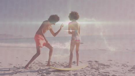 practicing surfing techniques, two people on sandy beach with ocean backdrop