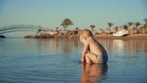 Quiet-little-boy-playing-with-toy-in-calm-water-near-beautiful-coastline.