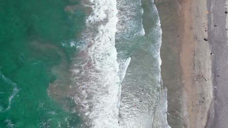 vista de arriba hacia abajo de las olas de la playa que se lavan en la costa cerca del muelle junto al mar con nadadores en el agua