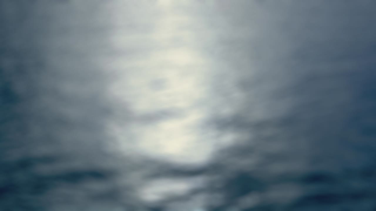 Moonlight  - Seamless loop of a completely defocused 4k-shot of a slightly wavy water surface. The reflected pale moonlight is shimmering on the water surface