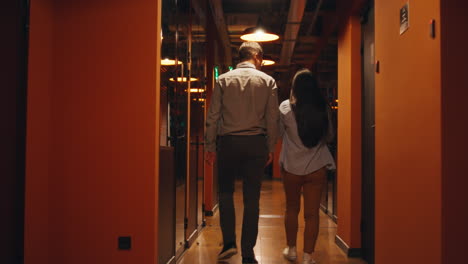 two people walking through a modern office hallway