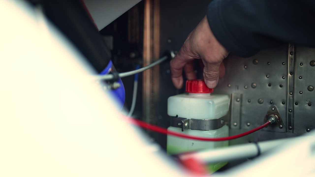Worker adjusting a fluid reservoir inside an industrial machine, ensuring smooth mechanical operation