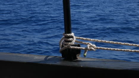 Close-up-of-a-boat-cleat-with-coiled-rope-on-deck,-tranquil-open-sea-background