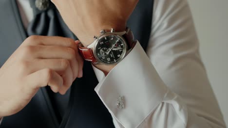 cerca de la mano de un hombre ajustando un reloj de pulsera de lujo con una correa de cuero