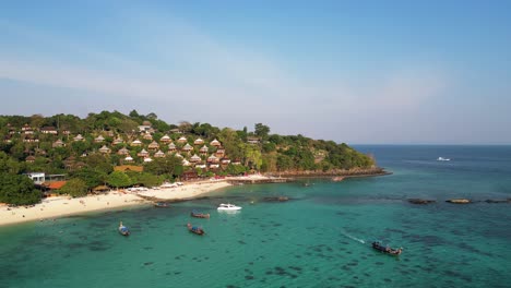 crystal clear water and boats near long beach, phi phi don, with hillside villas surrounded by lush greenery