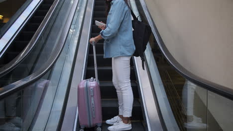 woman using escalator with luggage