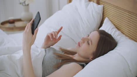 retrato de una mujer con ropa casual haciendo videollamadas de facetime con un teléfono inteligente en casa saludando a la gente en la pantalla del teléfono. usando la aplicación de reunión en línea de conferencias, distanciamiento social