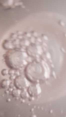 water swirls in plastic bottle with white nipple. air bubbles float on surface of clear liquid. drink saturates with oxygen during shaking. view from bottom of bottle macro
