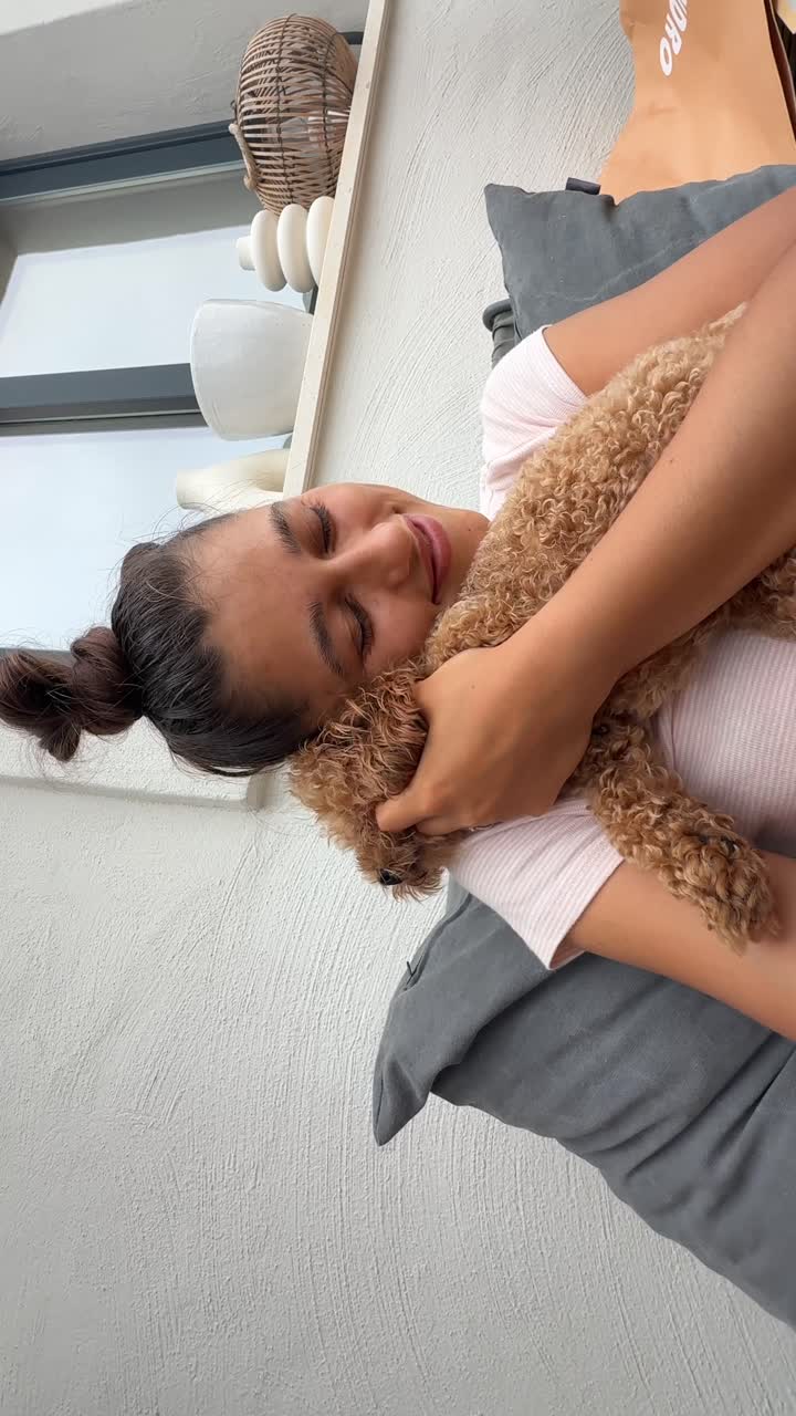Woman cuddling her adorable poodle on a porch
