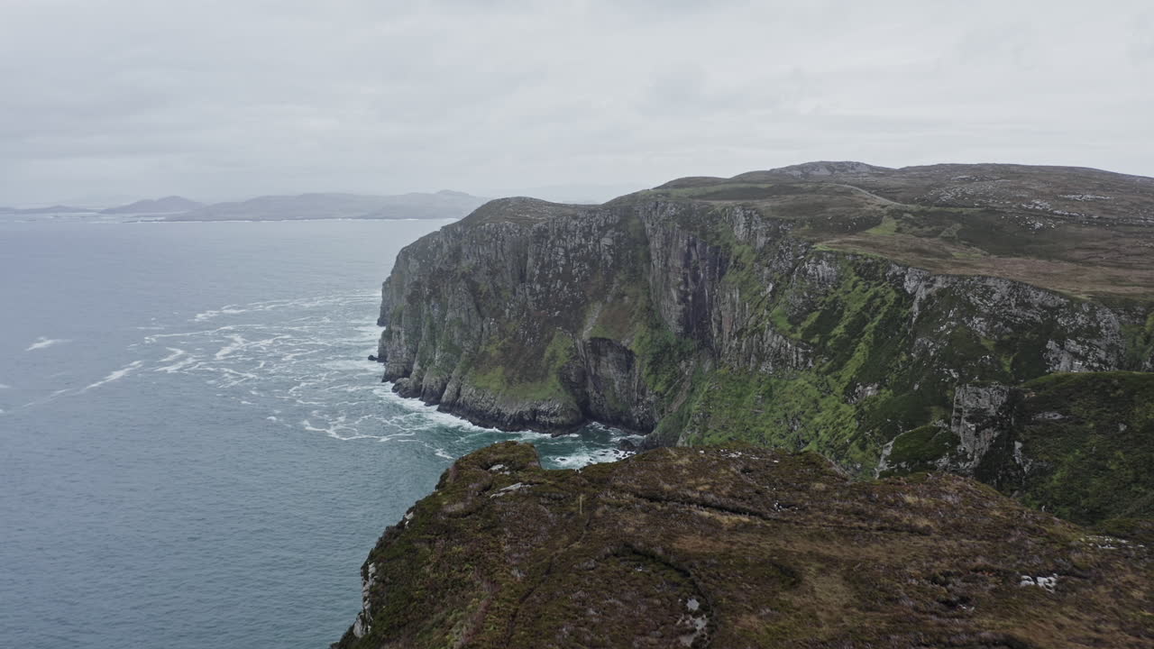 Experience the breathtaking cliffs of County Donegal as a drone captures sweeping views of the rugged coastline and crashing waves under a moody sky. A true sight of natural beauty.
