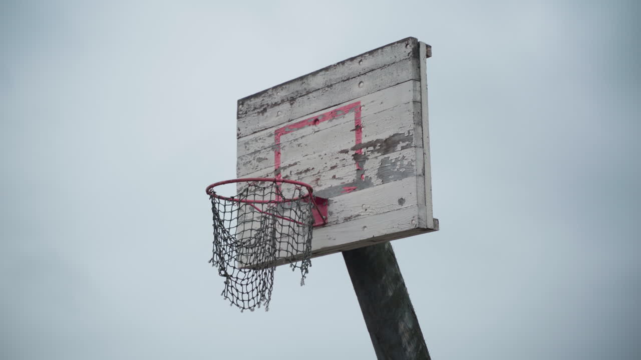 viejo aro de baloncesto con red rota colgando en el viento y pintura pelada