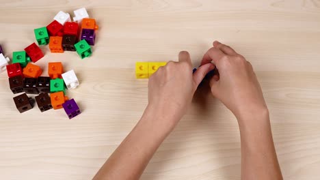 hands assembling colorful linking cubes on table