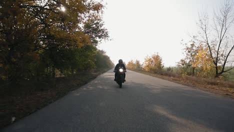 Front-view-of-a-man-in-black-helmet-and-leather-jacket-riding-motorcycle-on-a-country-road