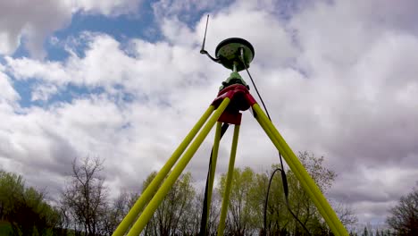 Moving-zoom-out-Timelapse-of-Leica-GNSS-base-station-for-land-surveying-with-clouds-moving-by,-on-a-summer-day-in-St